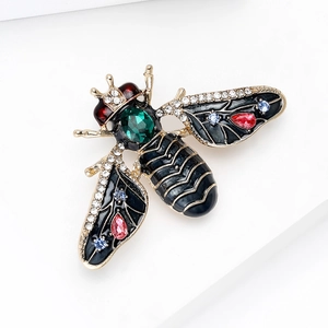 Elegant gold bee brooch with black enamel and emerald crystal on white steps