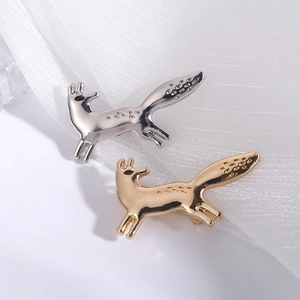 Minimalist fox brooches in gold and silver finish on white silk fabric background