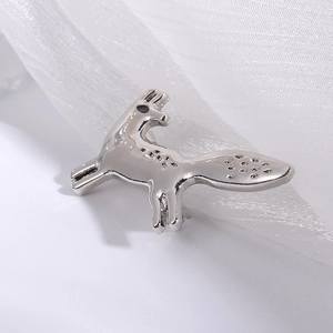 Macro detail of silver fox brooch with textured alloy surface and needle pin closure