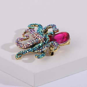Detailed macro view of an octopus brooch featuring teal crystals and a pink drop stone