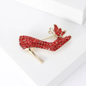 Detail der roten Strass-High-Heel-Brosche mit Goldlegierung auf weißem Hintergrund
