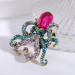 Golden octopus brooch with pink teardrop crystal and colorful rhinestones on white base