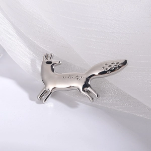 Minimalist silver fox brooch pin in a running pose on delicate white fabric