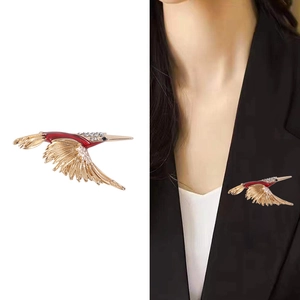 Goldene Kolibri-Brosche mit roter Emaille und Strass auf Model und weißem Hintergrund