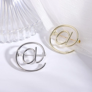 Minimalist @ symbol brooch in gold and silver metal finishes with a polished mirror shine
