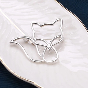 Détail d'une broche renard argentée ajourée sur une assiette décorative en céramique