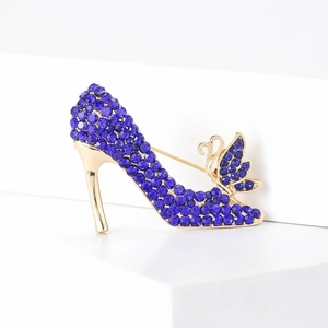 Eleganter High-Heel-Brosche mit blauen Strasssteinen und goldenem Schwan-Detail auf Weiß