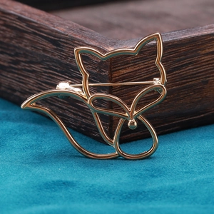 Détail d'une broche renard dorée ajourée sur boîte en bois avec texture métallique