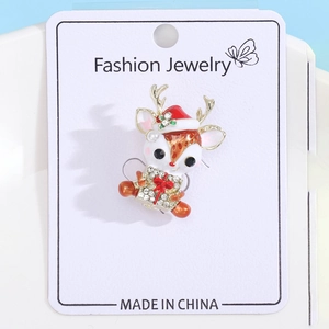 Détail d'une broche renne en émail avec bonnet de Noël rouge et boîte cadeau strass