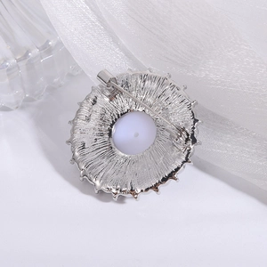 Macro detail of silver round brooch back showing radial texture and secure pin closure