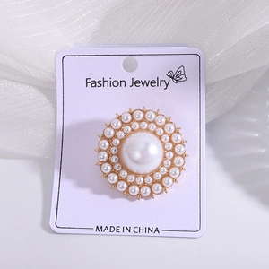 Detailed view of elegant pearl brooch with gold metal base on purple jewelry card