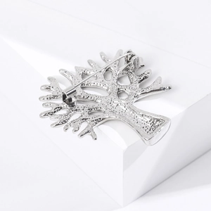 Gros plan du dos d'une broche arbre en argent montrant la texture polie et le fermoir épingle