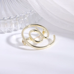Macro detail of gold @ symbol brooch showing the secure metal pin closure and texture