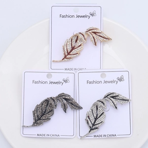 Detailed macro view of rhinestone-encrusted leaf brooches in red, black, and grey finishes
