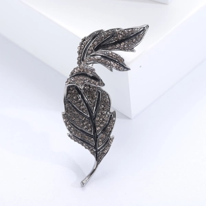 Vintage maple leaf brooch with smoky rhinestones on a minimalist white platform