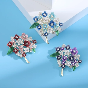Three elegant floral brooches with colorful enamel petals and sparkling crystal centers