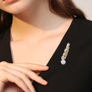 Elegant gold wheat brooch with marquise zircons and white pearl on black garment