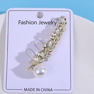 Detailed close-up of golden wheat ear brooch with marquise crystals and a white pearl