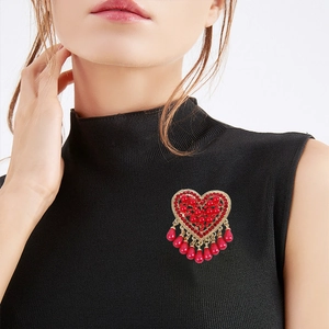 Elegant red heart brooch with crystal tassels and gold finish on black garment