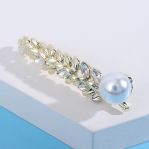 Macro shot of gold wheat-ear brooch with crystal leaves and a large white pearl bead