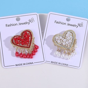 Detailed view of heart-shaped brooches with pearls, rhinestones and water drop pendants