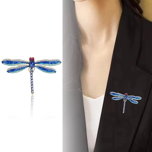 Elegant enamel dragonfly brooch with blue gemstones and diamonds on a black suit lapel