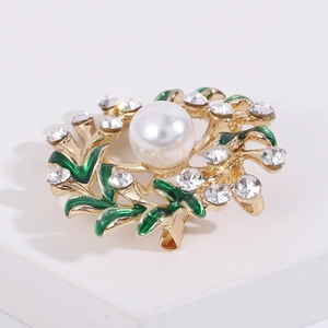 Detailed macro view of gold wreath brooch with green enamel leaves and white pearls