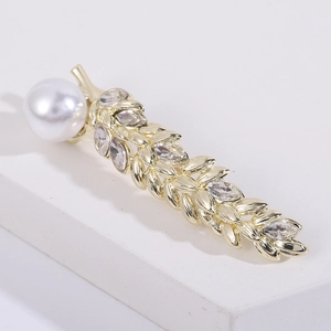 Elegant gold wheat brooch with crystal leaves and a white pearl on a white pedestal