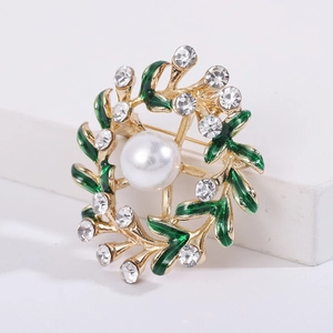 Close-up of floral wreath brooch with green enamel leaves, pearls and white crystals