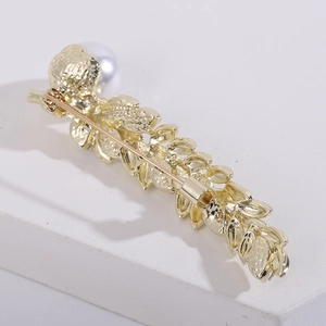 Macro detail of golden wheat brooch back showing secure pin clasp and metal texture