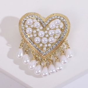 Detailed view of heart brooch with pearl inlay, rhinestones and teardrop tassels