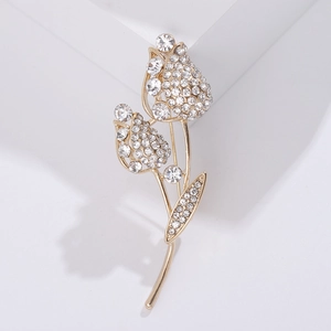 Gros plan sur une broche tulipe dorée sertie de strass brillants sur socle blanc
