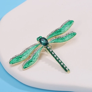 Detail of dragonfly brooch with green enamel wings and sparkling rhinestones on gold alloy