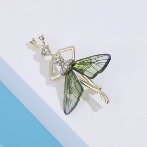 Detailed close-up of a golden ballerina brooch with green wings and white rhinestones