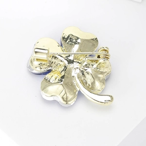 Detail view of the clover brooch back showing a secure golden pin clasp and metal craft