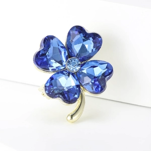Detailed macro view of four-leaf clover brooch with blue heart crystals and gold metal