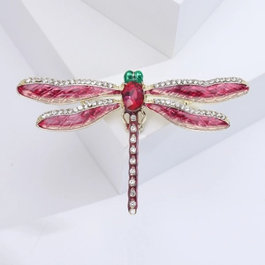 Detailed close-up of a dragonfly brooch with red enamel wings and sparkling rhinestones