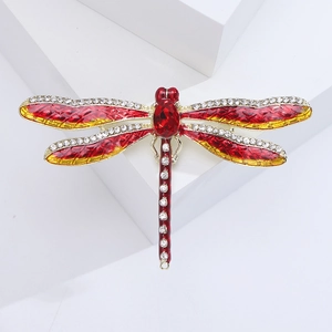 Close-up of red enamel dragonfly brooch with gold plating and sparkling white rhinestones