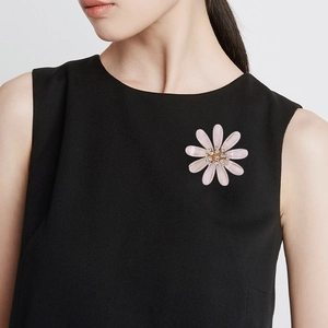 Elegant pink daisy flower brooch with rhinestones worn on a black sleeveless top