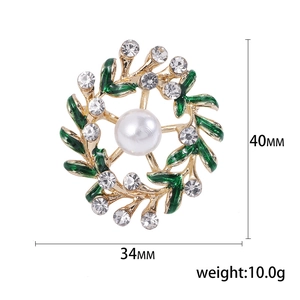 Floral wreath brooch with green enamel leaves, white pearl, and crystals on gold base