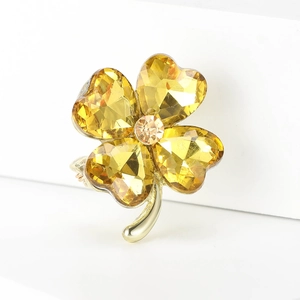 Detail of crystal four-leaf clover brooch in gold finish with faceted yellow crystals