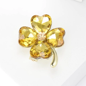Macro shot of gold clover brooch with amber crystal hearts and sparkling center stone