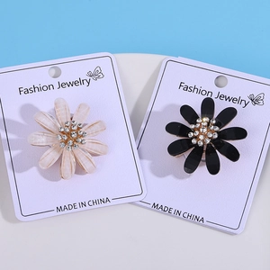 Macro detail of daisy flower brooches with rhinestones on fashion jewelry card