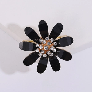 Detailed view of daisy flower brooch with black petals, crystal center, and gold plating