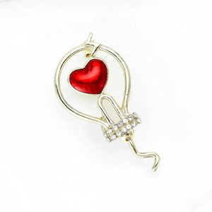 Spilla creativa a forma di lampadina dorata con cuore rosso e strass su sfondo bianco