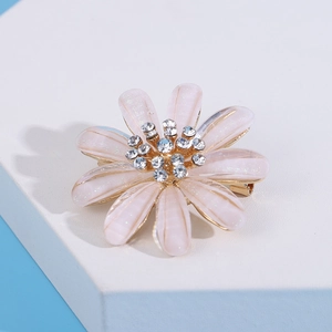 Detail of pink pearlescent daisy brooch with sparkling rhinestones and gold base