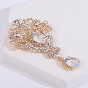 Detalle de broche vintage dorado con diamantes de imitación y colgante de gota fina