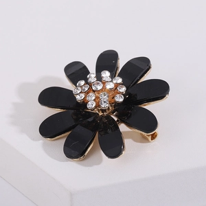 Macro detail of elegant black flower brooch with sparkling crystals and golden metal base