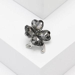Detailed view of silver clover brooch with dark gray heart-shaped crystal petals