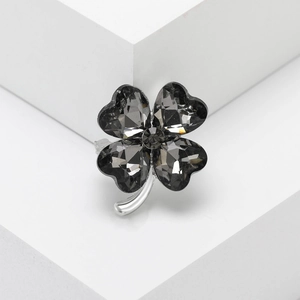 Minimalist four-leaf clover brooch with dark grey heart-shaped crystals on silver base